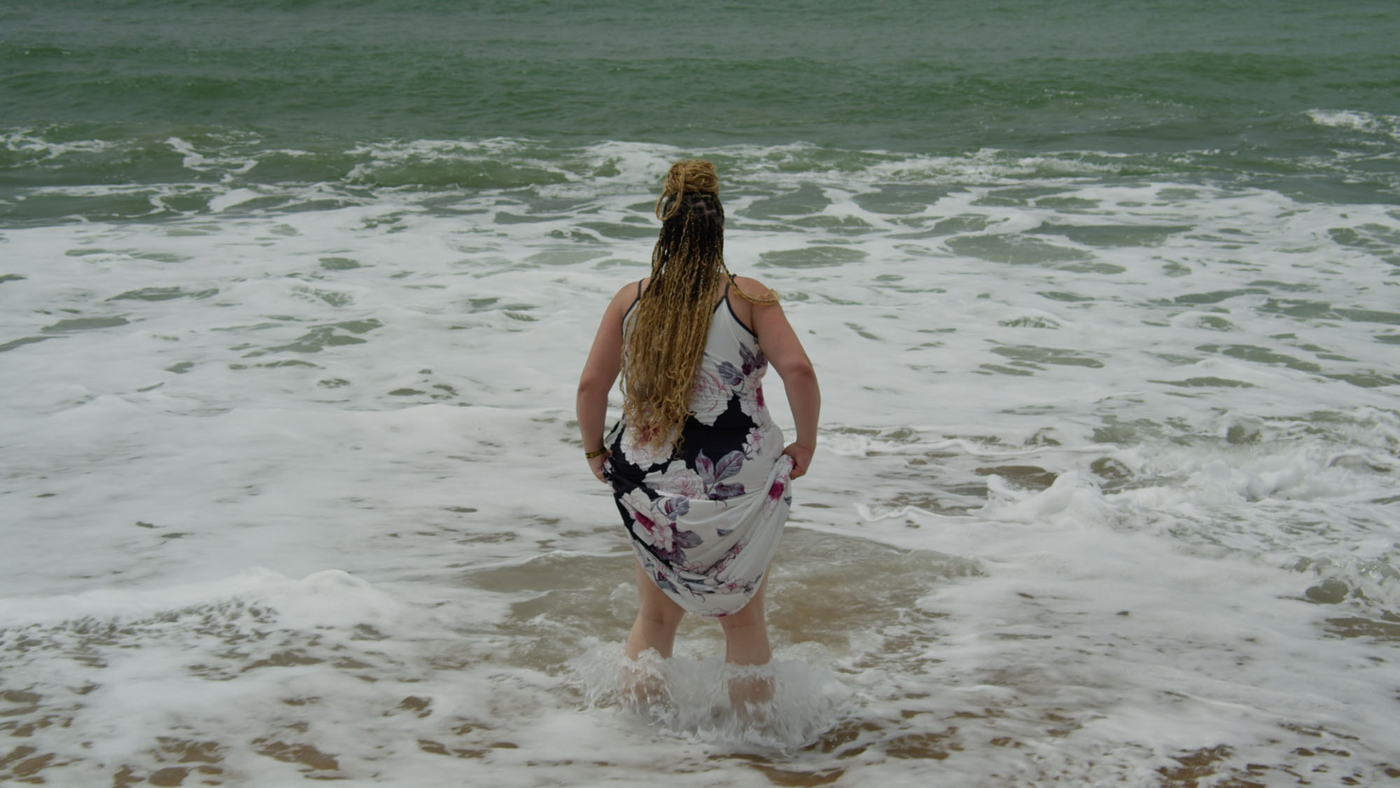 Still from The Unrooted Bloom — Amber Allen-Peirson wading into the ocean